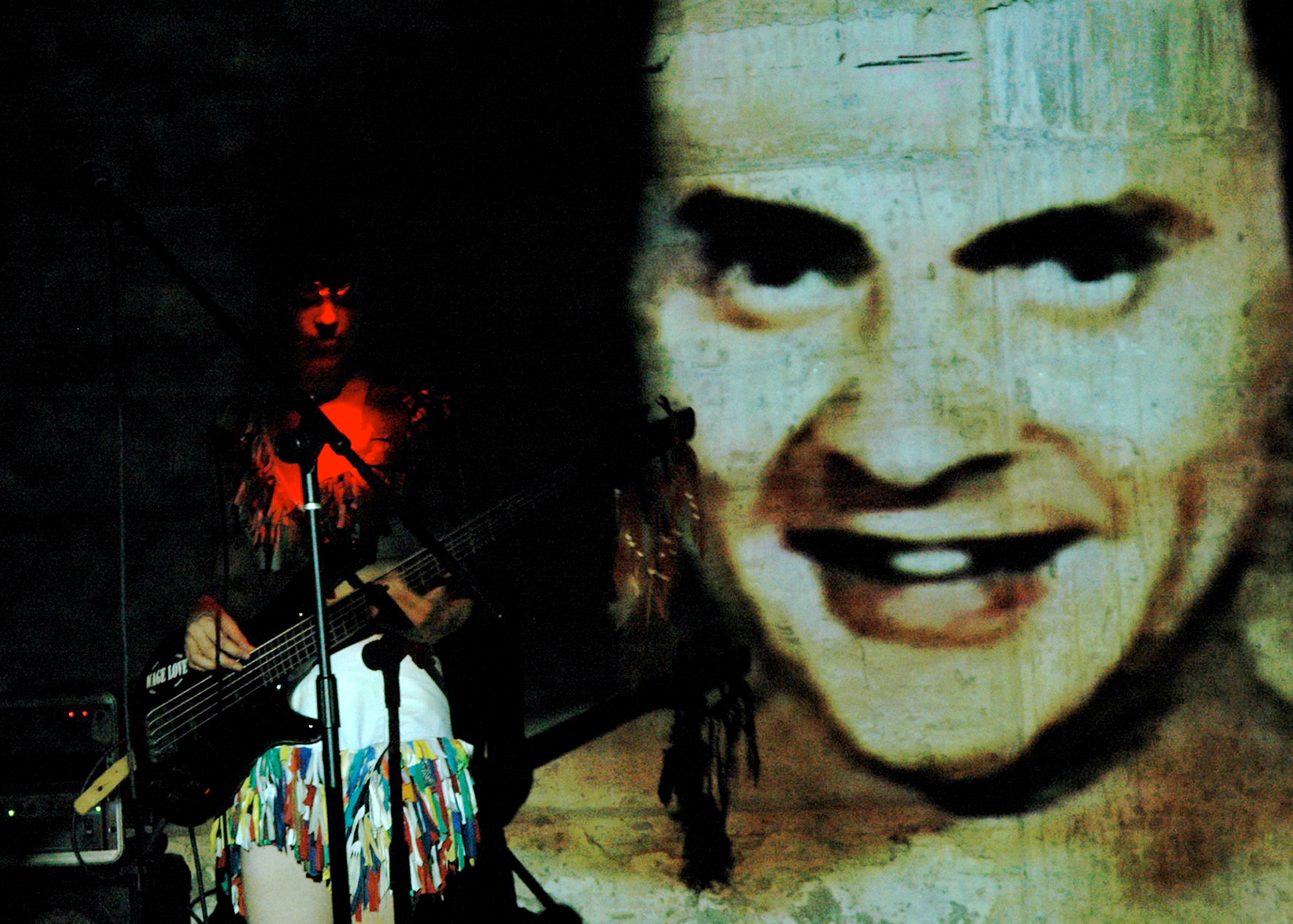 Caeser's face projected behind bassist